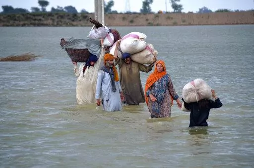 A displaced family wades through a flooded area after heavy rainfall, in Jaffarabad, a district of Pakistan's southwestern Baluchistan province, Aug. 24, 2022. A new study says human-caused climate change juiced the rainfall that triggered Pakistan's floods by up to 50%. But the authors of the Thursday, Sept. 15, study say other societal issues that make the country vulnerable and put people in harm's way are probably the biggest factor in the ongoing humanitarian disaster. (AP Photo/Zahid Hussa