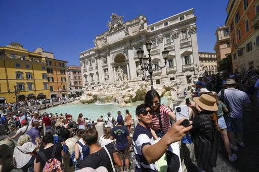 Tourists take a selfie in front of the Trevi Fountain, in Rome, Monday, June 20, 2022. Summer travel is underway across the globe, but a full recovery from two years of coronavirus could last as long as the pandemic itself. In Italy, tourists — especially from the U.S. — returned this year in droves. (AP Photo/Andrew Medichini)