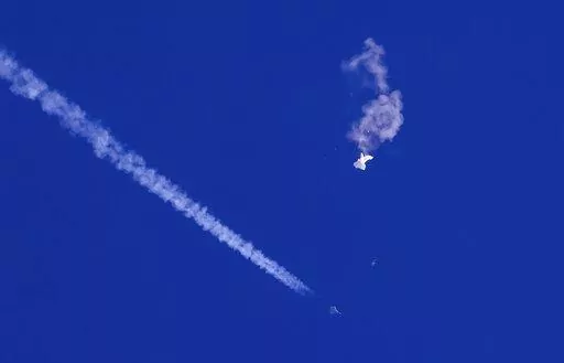 A fighter jet flies past the remnants of a large balloon after it was shot down above the Atlantic Ocean, just off the coast of South Carolina near Myrtle Beach, Feb. 4, 2023. The missile fired by a U.S. F-22 ended the days-long flight of what the Biden administration says was a surveillance operation that took the Chinese balloon near U.S. military sites. It was an unprecedented incursion across U.S. territory for recent decades, and raised concerns among Americans about a possible escalation i