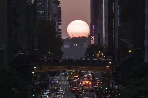FILE — The sun sets between buildings along 42nd Street in New York during a phenomenon known as Manhattanhenge, May 30, 2023. Wednesday, July 12, 2023, and Thursday, July 13, 2023 are the last two days of Manhattanhenge for the year, when jaded New Yorkers spill onto the streets to watch the sun set between the buildings that line the city's east-west corridors. But the forecast calls for clouds so there may not be much of a show. (AP Photo/Yuki Iwamura, File)