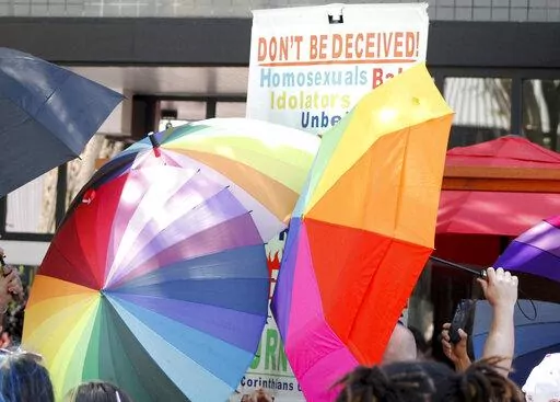 A sign-carrying anti-gay protester is surrounded by a sea of Pride umbrellas during the Pride parade in Winston-Salem, N.C., June 18, 2022. Hateful references to gays, lesbians and other LGBTQ Americans on social media surged following Florida's adoption of a law restricting how teachers can talk about sexual orientation with younger students. (AP Photo/Skip Foreman, File)