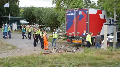 In this frame grab taken from video, policemen and rescuers stand at the site where a truck plowed into a gathering in the village of Nieuw-Beijerland, Netherlands, Saturday Aug. 27, 2022. A truck drove off a dike and slammed into a community barbecue in a village south of Rotterdam on Saturday killing and injuring several people. (Media TV via AP)
