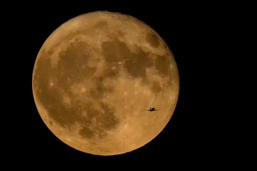 A commercial airliner flies Northwest across Lake Michigan in front of the "Full Buck" supermoon, the first of four supermoons in 2023, July 3, 2023, in Chicago. The cosmos is offering up a double feature in August: a pair of supermoons. Catch the first show Tuesday night, Aug. 2, as the full moon rises in the southeast. (AP Photo/Charles Rex Arbogast, File)