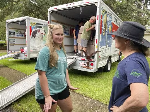 Medical student Emily Davis, left, speaks with her landlord Suzannah Thames on Friday, Aug. 26, 2022, as workers move furniture, appliances and other belongings out of a home Davis and her husband are renting in a flood-prone area of Jackson, Miss. After heavy rainfall, the Pearl River near Jackson is expected to flood some homes and businesses by Tuesday, Aug. 30, 2022. (AP Photo/Emily Wagster Pettus)
