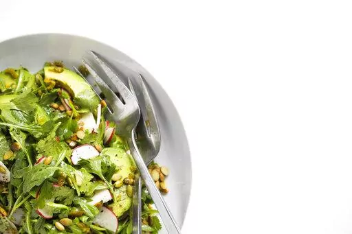 This image released by Milk Street shows a recipe for Arugula and Avocado Salad with Jalapeño Vinaigrette. (Milk Street via AP)