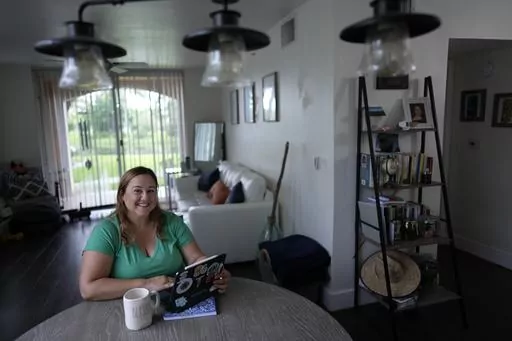 Melissa Lombana, 43, a high school teacher and mountain bike enthusiast, poses for a picture while working online, in her one-bedroom apartment in Miramar, Fla., Wednesday, July 26, 2023. Lombana's rent has increased each of the last two years and now amounts to nearly half her monthly income. "In a year, I will not be able to afford living here at all," she said. (AP Photo/Rebecca Blackwell)