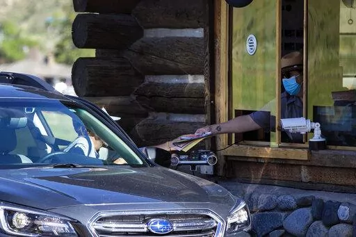 In this Monday, June 1, 2020 photo, a gate attendant at the North Entrance deals with visitors as the Montana entrances to Yellowstone National Park, in Wyoming, reopened after being closed due to COVID-19. On Friday, Dec. 23, 2022, The Associated Press reported on stories circulating online incorrectly claiming Yellowstone National Park officials have “closed down the park” due to a rising “volcanic uplift.” (Ryan Berry/Bozeman Daily Chronicle via AP, File)/Bozeman Daily Chronicle via A