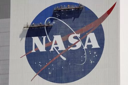 Workers on scaffolding repaint the NASA logo near the top of the Vehicle Assembly Building at the Kennedy Space Center in Cape Canaveral, Fla., May 20, 2020. (AP Photo/John Raoux, File)