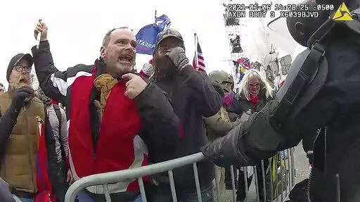 This still frame from Metropolitan Police Department body worn camera video shows Thomas Webster, in red jacket, at a barricade line at on the west front of the U.S. Capitol on Jan. 6, 2021, in Washington. More than 800 people across the U.S. have been charged in the Jan. 6 riot at the Capitol that left officers bloodied and sent lawmakers running in fear, and federal authorities continue to make new arrests practically every week (Metropolitan Police Department via AP)
