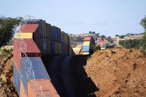 A long row of double-stacked shipping contrainers provide a new wall between the United States and Mexico in the remote section area of San Rafael Valley, Ariz., Thursday, Dec. 8, 2022. Work crews are steadily erecting hundreds of double-stacked shipping containers along the rugged east end of Arizona’s boundary with Mexico as Republican Gov. Doug Ducey makes a bold show of border enforcement even as he prepares to step aside next month for Democratic Governor-elect Katie Hobbs. (AP Photo/Ross