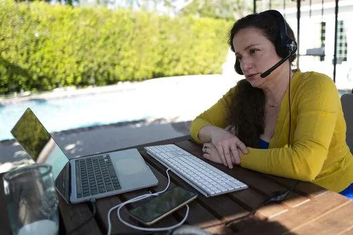 Julia Entin sits at her computer at her backyard office, coordinating efforts to rescue Holocaust survivors in Ukraine, Monday, March 14, 2022, in Los Angeles. (AP Photo/Richard Vogel)