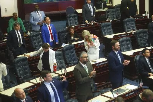Rep. Carlos Guillermo Smith, D-Orlando (blue suit, in back) yells his objection as Republicans in the House of Representatives applaud after Senate Bill 4C Independent Special Districts, which affects Disney, passes Thursday, April 21, 2022 at the Capitol in Tallahassee, Fla. The session was halted on a protest by Democrats, but continued after a brief recess. (AP Photo/Phil Sears)