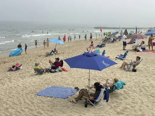 Beachgoers sit on chairs and under umbrellas at Ocean Grove, N.J., beach on Sunday, May 26, 2024. As the temperature heats up and summer approaches, small business owners may be considering offering summer hours, such as an early release on Fridays, for employees to help combat burnout. (AP Photo/Tassanee Vejpongsa, File)