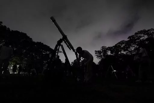 A girl looks at the moon through a telescope in Caracas, Venezuela, on Sunday, May 15, 2022. The best day to spot five planets, Mercury, Jupiter, Venus, Uranus and Mars, lined up in the night sky is Tuesday, March 28, 2023, right after sunset. The five-planet array will be visible from anywhere on Earth, as long as you have clear skies. (AP Photo/Matias Delacroix)