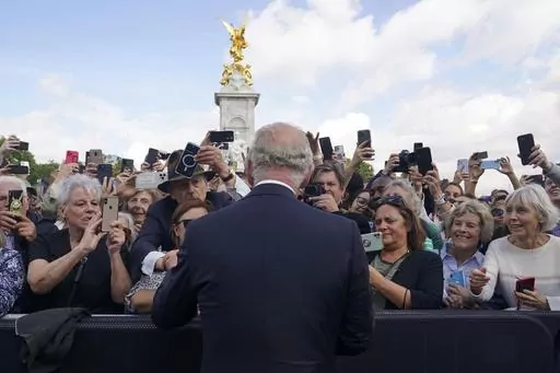 Britain's King Charles III, back to camera, greets well-wishers as he walks by the gates of Buckingham Palace following Thursday's death of Queen Elizabeth II, in London, Friday, Sept. 9, 2022. King Charles III will be crowned Saturday, May 6, 2023 at Westminster Abbey in an event full of all the pageantry Britain can muster. (Yui Mok/Pool Photo via AP, File)