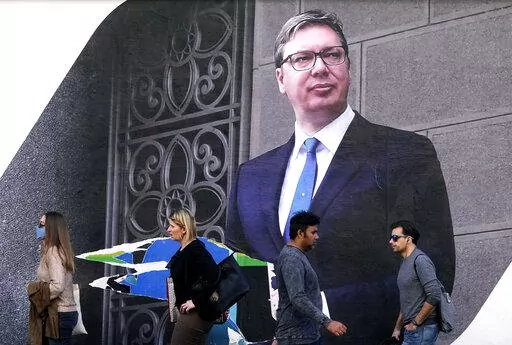 People walk by the pre-election billboard showing Current Serbian President and the Serbian Progressive Party leader Aleksandar Vucic in Belgrade, Serbia, Monday, March 28, 2022. Serbia's populist President Aleksandar Vucic, who has fostered close ties with Russia and refused to impose sanctions against Moscow over its invasion of Ukraine, is expected to extend his almost 10-year grip on power in the Balkan country at an election on Sunday. (AP Photo/Darko Vojinovic)