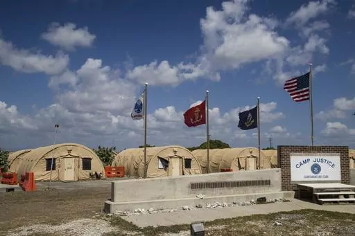 In this photo reviewed by U.S. military officials, flags fly in front of the tents of Camp Justice in Guantanamo Bay Naval Base, Cuba, on April 18, 2019. For the first time since the facility in Cuba opened in 2002, a U.S. president had allowed a United Nations independent investigator, Fionnuala Ní Aoláin, to visit. (AP Photo/Alex Brandon, File)