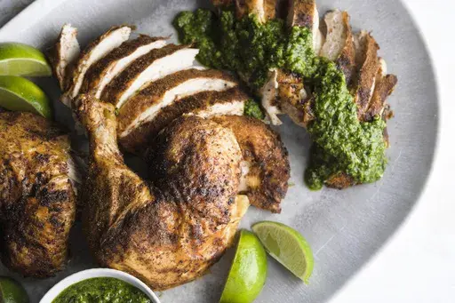 This image released by Milk Street shows a recipe for spice-rubbed roasted chicken with green-herb chutney. (Milk Street via AP)