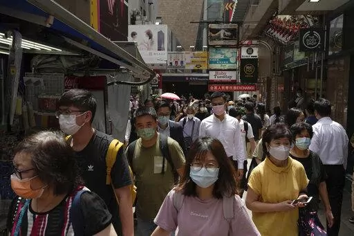 People wearing face masks walk along a side street in Mongkok, a shopping district of Hong Kong, Monday, Aug. 8, 2022. Hong Kong will reduce the mandatory hotel quarantine for overseas arrivals to three days from a week, the city's leader said Monday. (AP Photo/Kin Cheung)