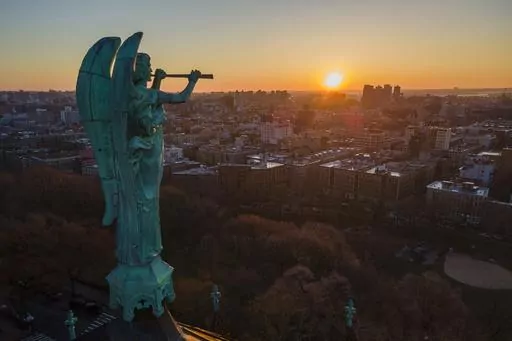 A bronze statue of the Archangel Gabriel blowing a trumpet stands atop the Cathedral of St. John the Divine as the sun rises in the Morningside Heights neighborhood of the borough of Manhattan in New York City on Sunday, March 26, 2023. The county that encompasses Manhattan added more than 17,000 residents in the year ending last July after losing almost 111,000 people in the previous 12-month period, according to population estimates released Thursday, March 30, 2023, by the U.S. Census Bureau.