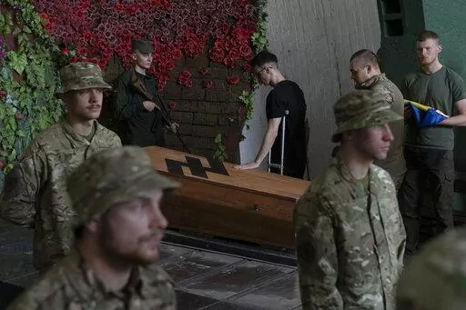 Soldiers of the Azov regiment pay their last respects to a serviceman killed in battle against Russian troops, in a city crematorium in Kyiv, Ukraine, Thursday, July 21, 2022. (AP Photo/Andrew Kravchenko)