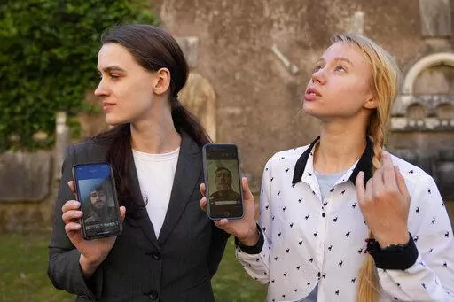 Kateryna Prokopenko, wife of Denys Prokopenko, commander of the Azov regiment, right, and Yulia Fedosiuk, wife of Arseny Fedosiuk, another member of Azov regiment get emotional as they show photos of their husbands on their phones during an interview with the Associated Press in Rome, Friday, April 29, 2022. Two Ukrainian women whose husbands are defending a besieged steel plant in the southern city of Mariupol are calling for any evacuation of civilians to also include soldiers. They say the tr