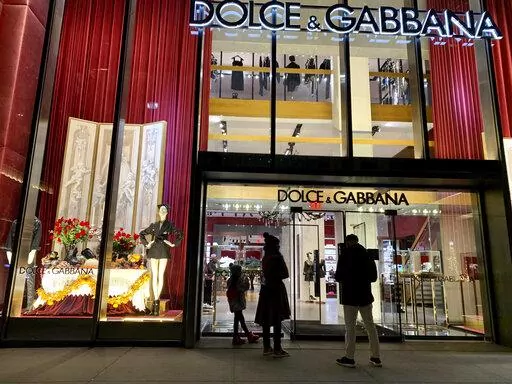 People stand outside the Dolce & Gabbana store on Fifth Avenue, Nov. 21, 2021, in New York. Dolce & Gabbana announced Monday, Jan. 31, 2022 that it will drop the use of animal fur in all its collections starting this year, and transition to eco-friendly faux fur. The Milan fashion house joins other luxury brands, including Armani, Gucci, Prada and Moncler, in adhering to guidelines set by the Fur Free Alliance, a network of animal rights groups around the world. (AP Photo/Pamela Hassell, file)