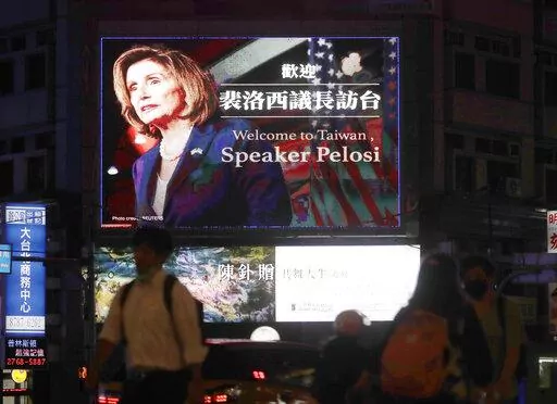 People walk past a billboard welcoming U.S. House Speaker Nancy Pelosi, in Taipei, Taiwan, Tuesday, Aug 2, 2022. Pelosi has arrived in Taiwan and becomes the highest-ranking American official in 25 years to visit the self-ruled island claimed by China, which quickly announced that it would conduct military maneuvers in retaliation for her presence.  (AP Photo/Chiang Ying-ying)