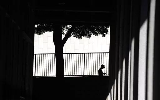A person is silhouetted against a wall as they look down at their cell phone outside the Clara Shortridge Foltz Criminal Justice Center on July 29, 2021, in Los Angeles. With abortion now or soon to be illegal in over a dozen states and severely restricted in many more, Big Tech companies that vacuum up personal details of their users are facing new calls to limit that tracking and surveillance. One fear is that law enforcement or vigilantes could use those data troves against people seeking way