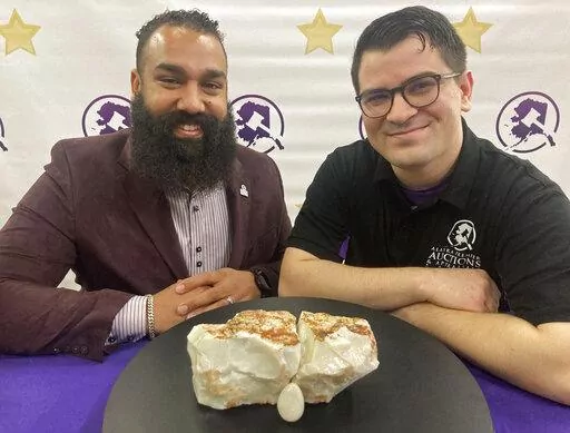 CORRECTS TO ALASKA PREMIER AUCTIONS AND APPRAISALS Dan Newman, left, the founder of Alaska Premier Auctions and Appraisals, and Nick Cline, a business partner, pose Friday, Feb. 18, 2022, in Anchorage, Alaska, with the "Americus Australis," thought to be one the largest gem-quality opals in existence. The gem will be offered at auction Sunday, Feb. 20, 2022, with an opening bid set at $125,000 (AP Photo/Mark Thiessen)