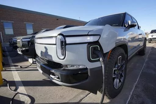 A 2023 R1T pickup truck is charged in a bay at a Rivian delivery and service center Wednesday, Feb. 8, 2023, in Denver. Electric vehicle maker Rivian says it will follow General Motors and Ford and join Tesla's charging network next year. The startup truck, SUV and delivery van maker says Tuesday, June 20, that like GM and Ford, it will include ports with Tesla’s connector on future Rivian vehicles starting in 2025. (AP Photo/David Zalubowski, File)