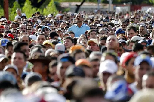 A man peaks over the crowd waiting on the Simon Bolivar bridge to cross the border into Colombia, to hunt for food and medicine in San Antonio del Tachira, Venezuela, July 17, 2016. Over the last 10 years, more than 7.1 million people have left Venezuela amid a political, economic and humanitarian crisis that has marked the entirety of President Nicolas Maduro’s government. (AP Photo/Ariana Cubillos, File)