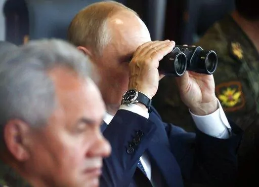 Russian President Vladimir Putin, center, watches through binoculars as Russian Defense Minister Sergei Shoigu sits near during the joint strategic exercise of the armed forces of the Russian Federation and the Republic of Belarus Zapad-2021 at the Mulino training ground in the Nizhny Novgorod region, Russia, on Sept. 13, 2021. Putin's threats to use "all the means at our disposal" to defend his country as it wages war in Ukraine have cranked up global fears that he might use his nuclear arsenal