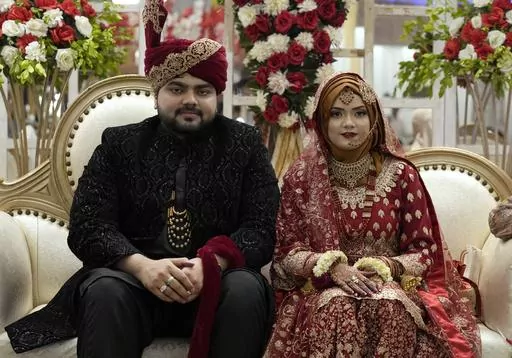 Pakistani bride Dua Khan and groom Asher Khan pose for photo during their wedding ceremony at Radiance banqueting hall, in Karachi, Pakistan, Saturday, Jan. 27, 2024. There's a scrum of people trying to get photos with the married couple at the Radiance banqueting hall in a middle-class Karachi neighborhood Voices are barely audible above the din of 400 guests, dinner service, music, and the drone whirring around the room. The bride and groom are beaming. Their families and friends jostle for a 
