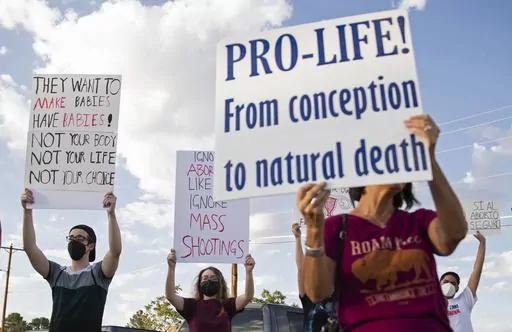 An anti-abortion advocate along with abortion rights advocates hold up signs during the Emergency Pro-Life Rally for New Mexico in Las Cruces, N.M., July 19, 2022. The New Mexico Supreme Court blocked local anti-abortion ordinances Friday, March 31, 2023, pending the outcome of a case centered on constitutional rights to equal protection and due process. (Meg Potter/The Las Cruces Sun News via AP, File)