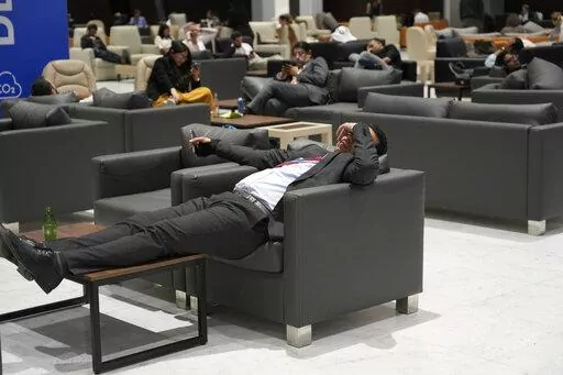 Attendees and members of the media lounge as they wait for a closing plenary session at the COP27 U.N. Climate Summit, Sunday, Nov. 20, 2022, in Sharm el-Sheikh, Egypt. (AP Photo/Peter Dejong)