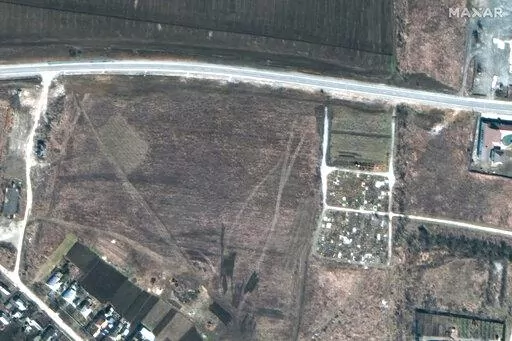 This satellite image provided by Maxar Technologies on Thursday, April 21, 2022 shows an overview of the cemetery in Manhush, some 20 kilometers west of Mariupol, Ukraine, on March 19, 2022. (Satellite image ©2022 Maxar Technologies via AP)