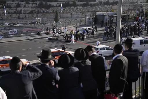 People look at Israeli police officers and volunteers from the Zaka rescue service work at the shooting attack in Jerusalem, Thursday, Nov. 30, 2023. The shooting death of an Israeli man who raced to confront Palestinian attackers has raised questions about the use of excessive force among Israeli security forces and the public. The man's shooting mirrors previous incidents where Israeli security forces or civilians have opened fire on attackers who no longer appear to pose a threat or on suspec