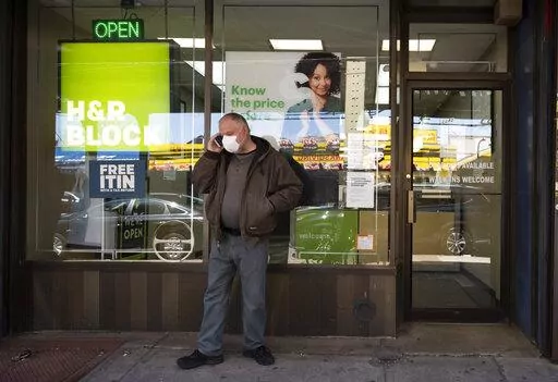A man waits outside a H&R Block tax preparation office on Monday, April 6, 2020, in the Brooklyn borough of New York. Tax season is here again. Whether you do your taxes by yourself, go to a tax clinic or hire a professional, navigating the tax system can be complicated. (AP Photo/Mark Lennihan, File)