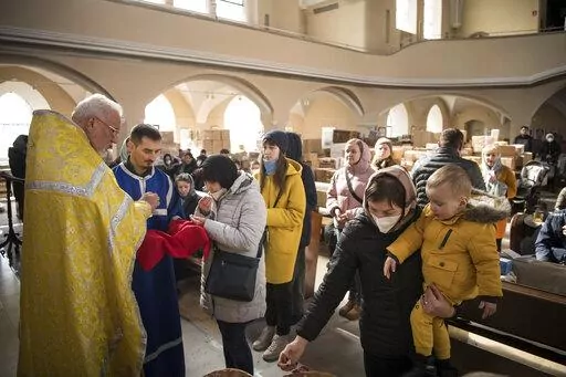 Members of the Ukrainian Orthodox community, who have found shelter for their church service in an evangelical church, and refugees from Ukraine celebrate a church service and pray for peace in Berlin, Sunday, March 20, 2022. (AP Photo/Steffi Loos)