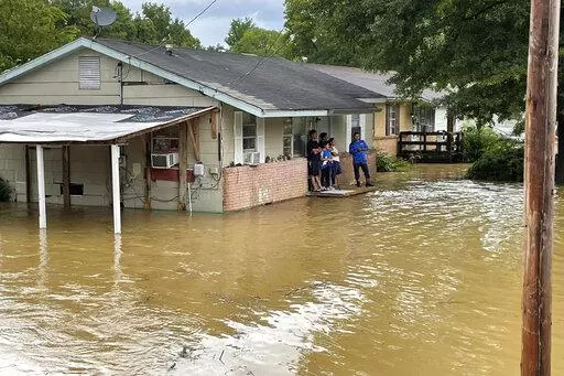 A Canton, Miss., family waits to be rescued, Tuesday, Aug. 2, 2022, after torrential rain caused a creek on Martin Luther King Drive to rise, from the resulting floodwater. A number of residents were trapped in their low-level homes due to the severe flash flooding from the morning rains. (Chris Fields/WLBT via AP)